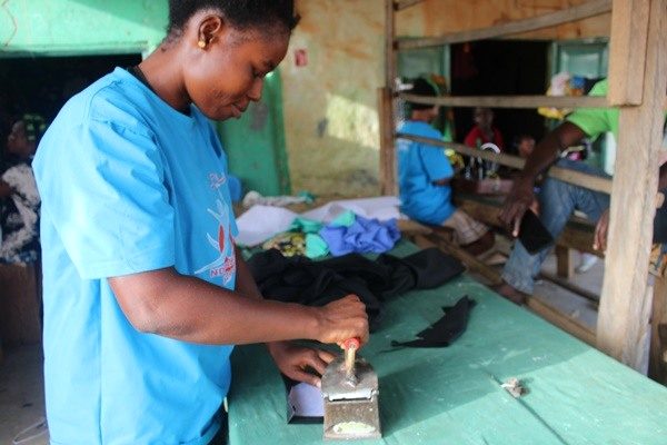 A person in a blue Foundation shirt presses fabric on a workshop table.