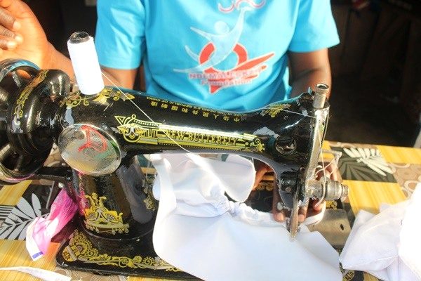 Close view of a black sewing machine with white fabric under the needle.